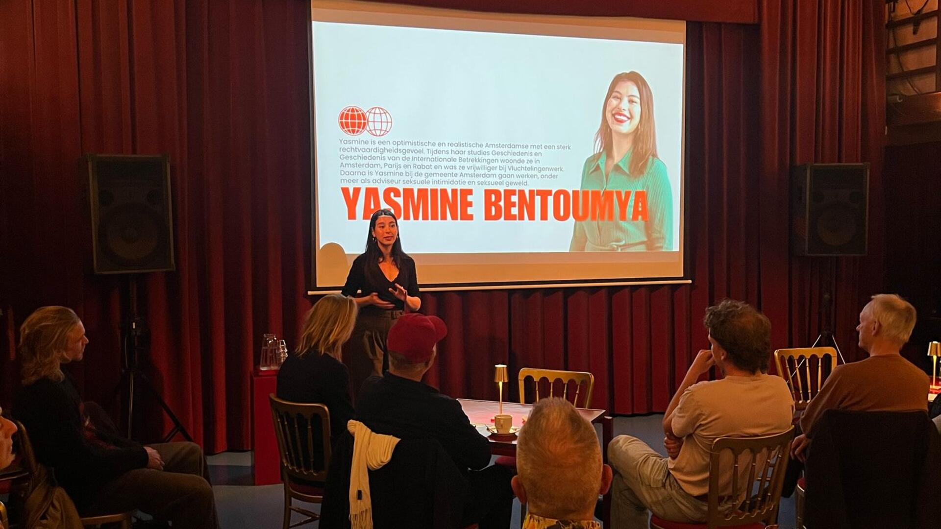 Foto van Yasmine Bentoumya die een zaal vol leden toespreekt over Reclaim het Centrum